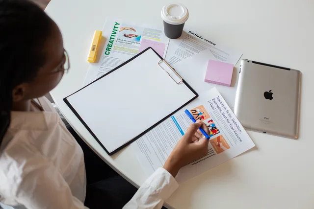 Top view of a woman reviewing various documents with a clipboard on a desk. Reputation management planning template for software