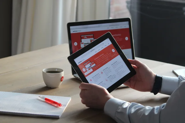 Business professional using a tablet and laptop with a hot drink, focusing on digital content review. Scoping a review-platform comparison by task
