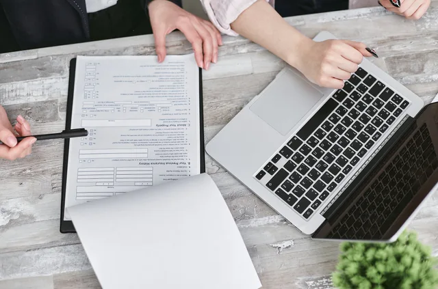 Two people collaborating over documents and laptop in modern office setting. Reputation management reporting dashboard: reconciliation first